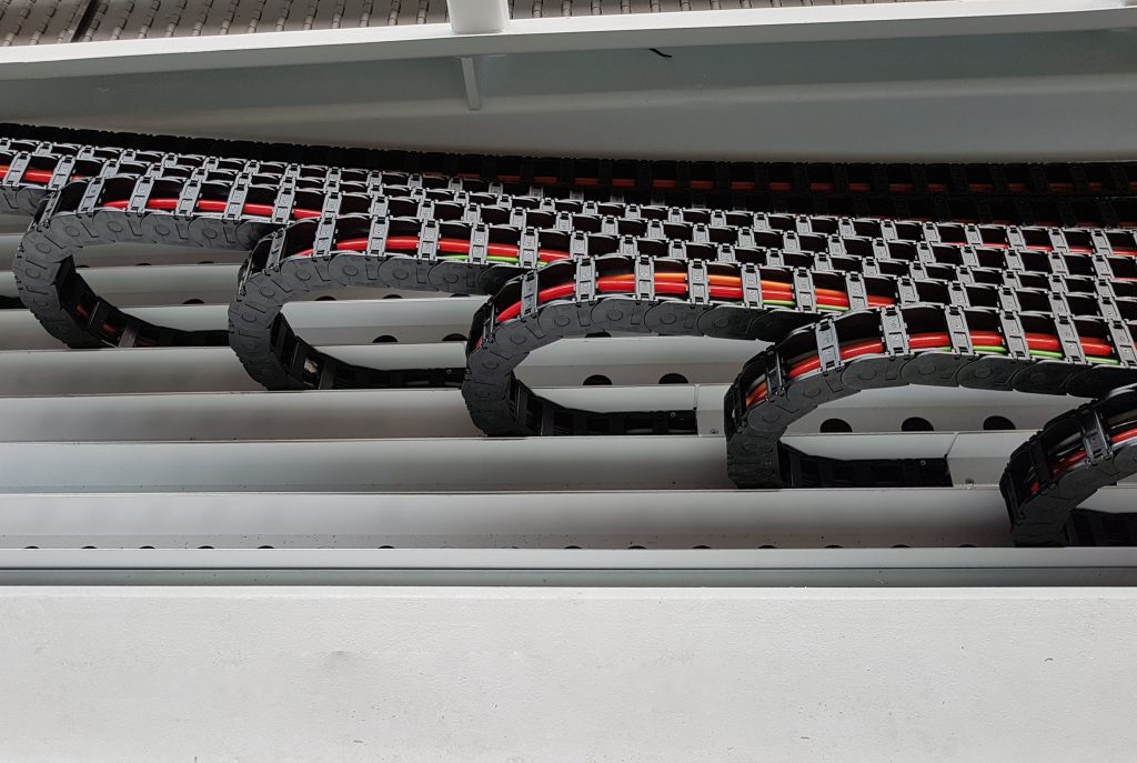 Die 16 Spannbalken werden jeweils über eine Igus Energiekette mit einem Verfahrweg von 12,5m mit Energie und Signalen versorgt. – Bild: igus GmbH